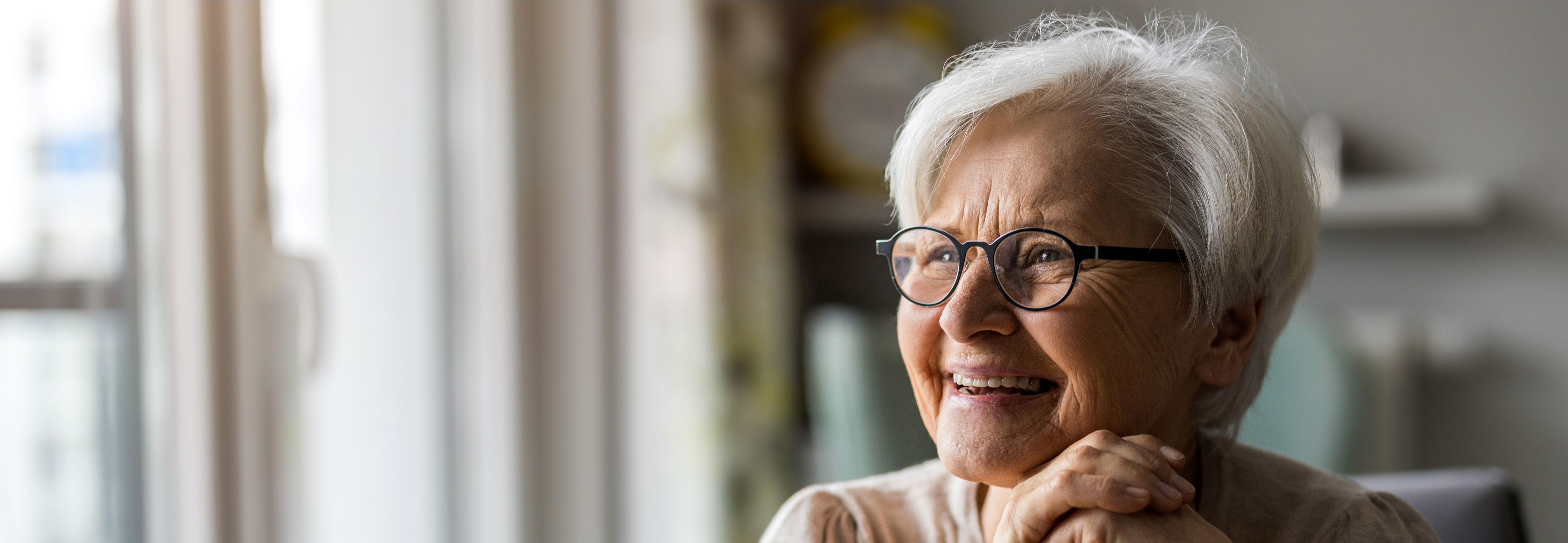 An older female wearing glasses and smiling.