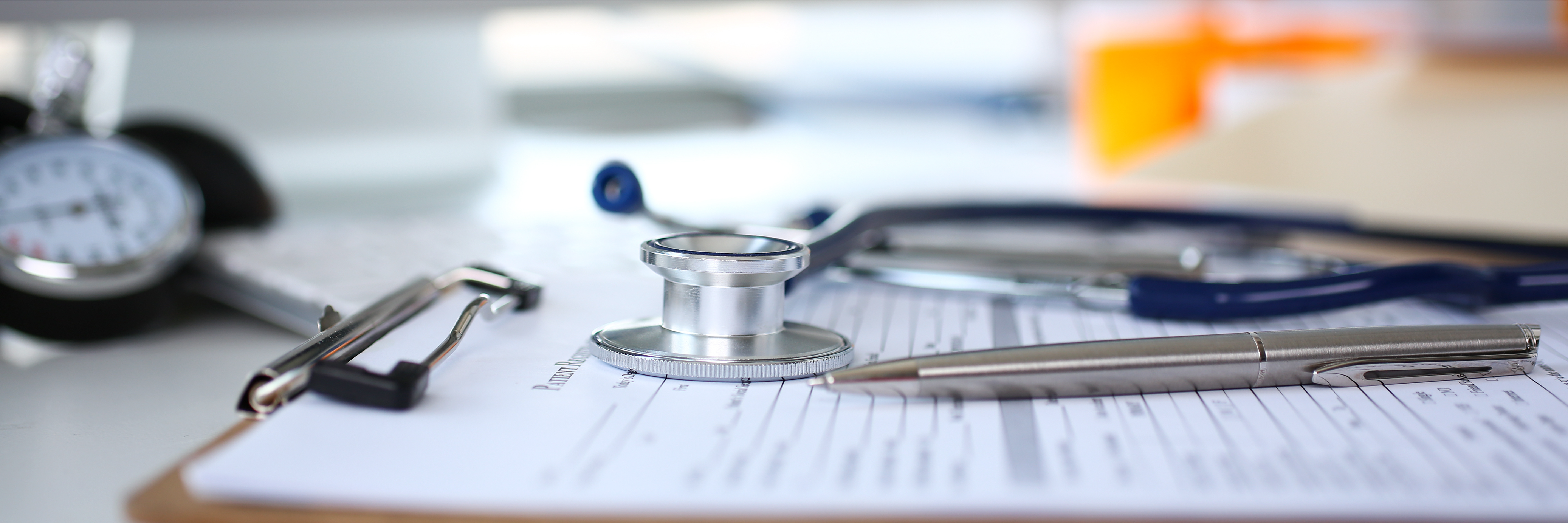 Clipboard with paperwork and a stethoscope sitting on of a countertop.